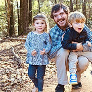 Adalyn is registered to the contest to win money with this photo: child, children, man, forest, trees, outdoor, nature, smile, happy, boy, girl, family, casual_clothing, walking_path, daylight, leaves, pants, shirt, sneakers, beard