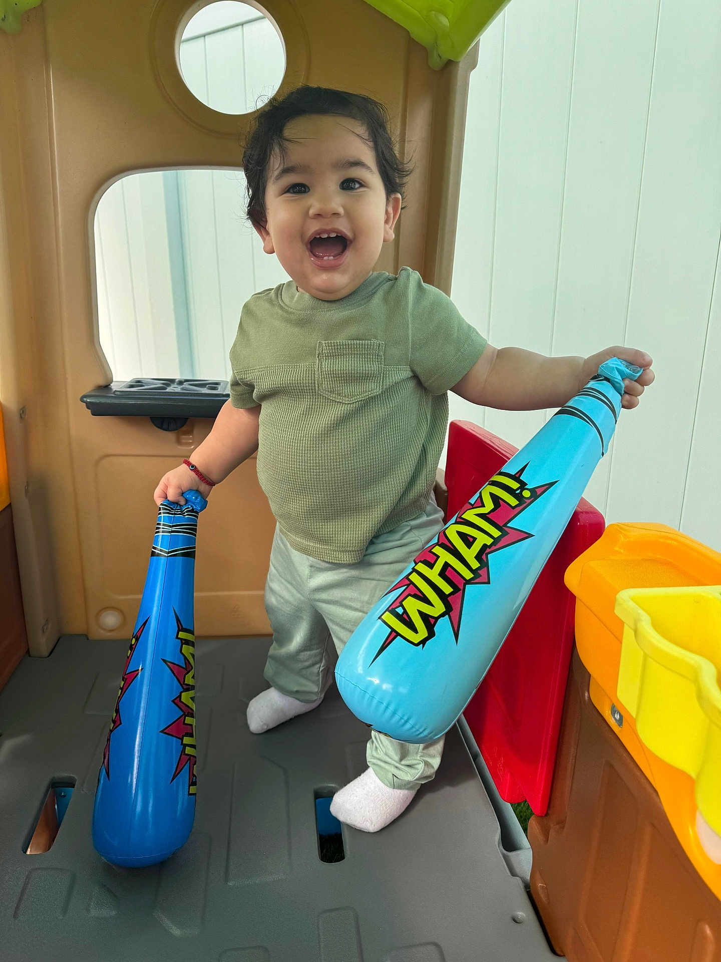 Eithan is registered to the contest to win money with this photo: toddler, child, playhouse, inflatable_bats, blue, smiling, happy, toy, indoor, green_shirt, pants, socks, play, fun, cute, person, small, young_child, joyful, expression