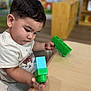 toddler, child, toy, building_blocks, table, indoor, play, concentration, short_hair, casual_clothing, seat, wooden_furniture, colorful, young_child, cute, hand, face, expression, learning, early_education