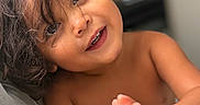 Lucas Valentino is registered to the contest to win money with this photo: ball, bare_shoulders, brown_hair, candid, child, close_up, colorful, couch, curly_hair, eyes, face, happy, indoor, photography, portrait, sitting, smiling, teeth, toddler, toy