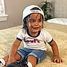 Lucas Valentino is registered to the contest to win money with this photo: child, toddler, portrait, smiling, sitting, bedroom, bed, baseball_cap, backwards_cap, wet_hair, denim_shorts, t_shirt, sneakers, white_socks, indoors, home, bedding, plant, fashion, happy
