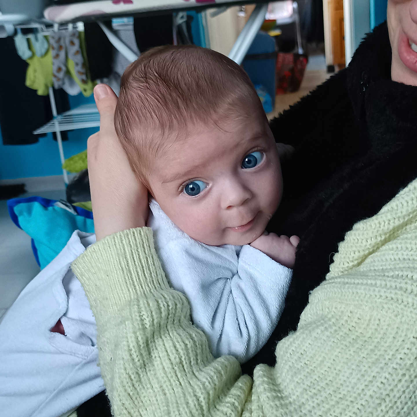 Lorraine a rejoint le concours — aidez-le/la à gagner de superbes lots ! adult, baby, blue_eyes, closeup, clothing, expression, face, furniture, hand, holding, home, human, indoor, infant, laundry, person, portrait, skin, sweater, yellow_clothing