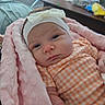 Adalyn joined the competition — help win amazing prizes! baby, infant, pink_blanket, headband, bow, orange_outfit, checkered, face, portrait, indoor, table, furniture, soft_texture, cozy, child, newborn, human, resting, wrapped, cute