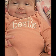 Adalyn is registered to the contest to win money with this photo: baby, child, infant, smiling, portrait, close_up, indoors, blanket, pink, peach_clothing, onesie, bestie_text, minnie_mouse, cartoon, lying_down, face, hands, hair, cute, photograph