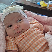 Adalyn is registered to the contest to win money with this photo: baby, infant, headband, bow, orange_checkered, blanket, pink, clothing, face, portrait, indoor, soft, cute, newborn, child, person, cozy, resting, closeup, expression