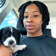 Oreo joined the competition — help win amazing prizes! person, puppy, dog, car, selfie, twist_hairstyle, black_hair, white_puppy_paw, window, sky, clouds, seat, casual_clothing, hand, face, portrait, indoor, daylight, calm, cute