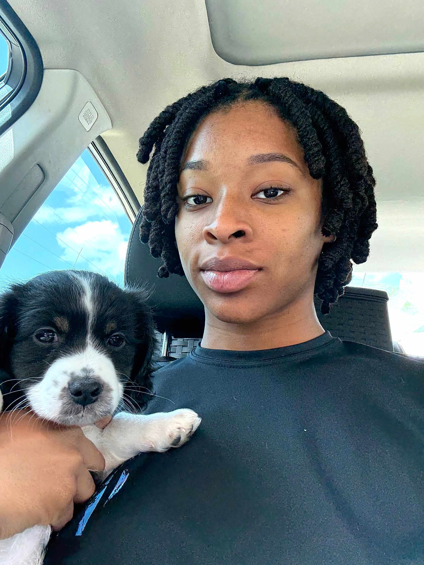 Oreo joined the competition — help win amazing prizes! person, puppy, dog, car, selfie, twist_hairstyle, black_hair, white_puppy_paw, window, sky, clouds, seat, casual_clothing, hand, face, portrait, indoor, daylight, calm, cute