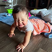 Sahily is registered to the contest to win money with this photo: baby, crawling, striped_clothing, wooden_floor, toy, blanket, pillow, indoor, smile, cute, child, floor, furniture, earring, person, home, playtime, happy, expression, infant
