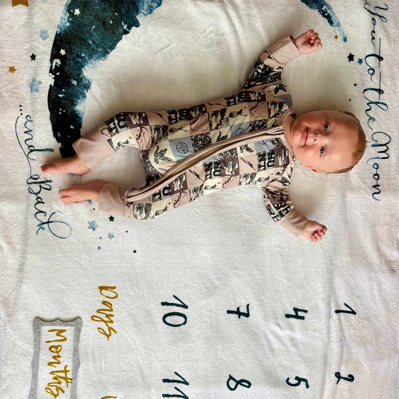 Carson joined the competition — help win amazing prizes! age_marker, baby, blanket, blue_eyes, child, cozy, crescent_moon, face, infant, light_hair, lying_down, numbers, onesie, patterned_clothing, portrait, script_text, smiling, soft_texture, stars, yellow_star_frame