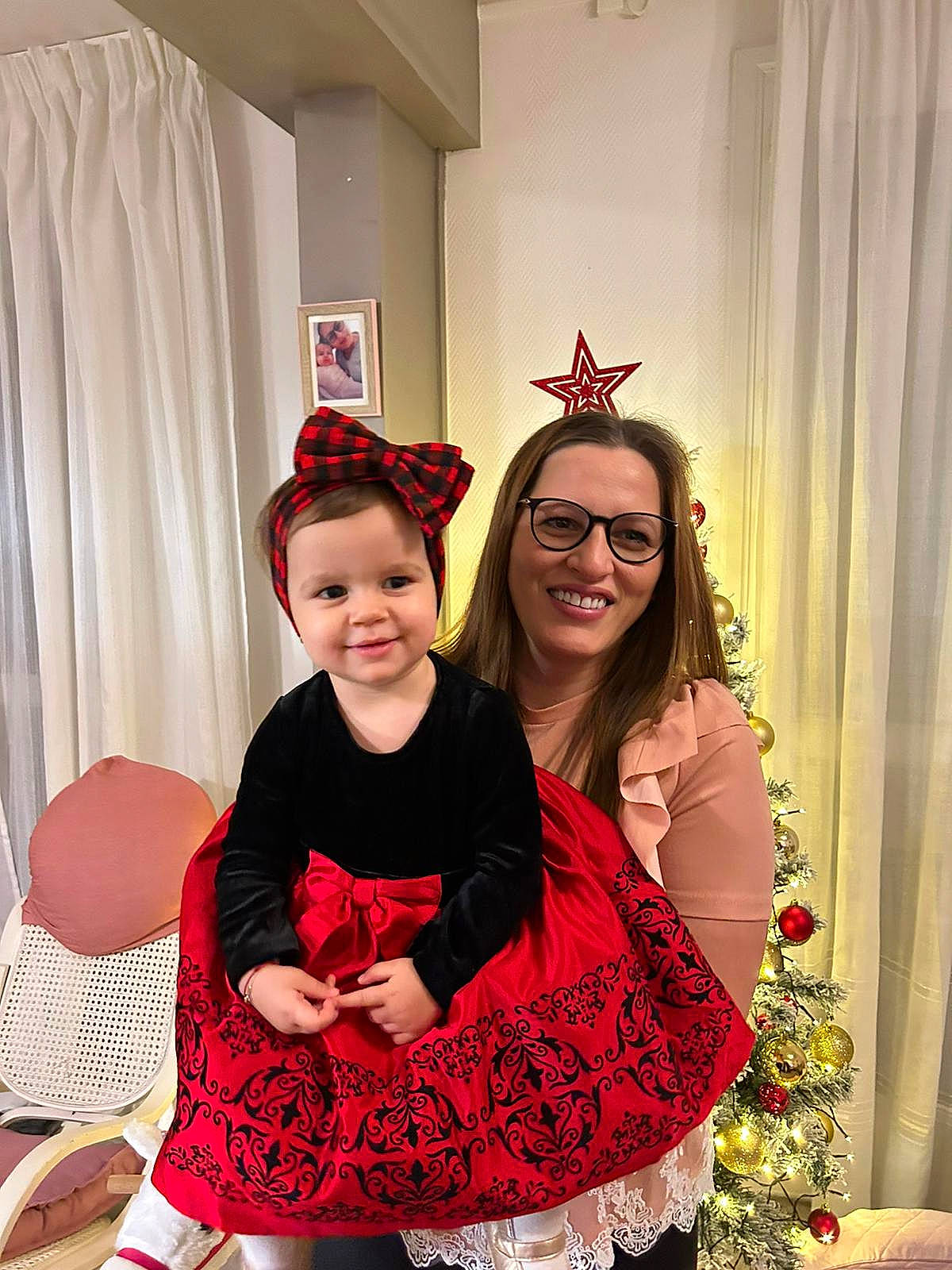 Sophia Maria participe au concours pour gagner de l'argent avec cette photo : christmas_decoration, christmas_eve, christmas_ornament, curtain, event, eyewear, facial_expression, fashion, fashion_design, fun, happy, holiday, joy, person, red, room, sleeve, smile, sunglasses, toddler