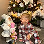Naël a rejoint le concours — aidez-le/la à gagner de superbes lots ! child, pajamas, plaid, christmas_tree, christmas_decorations, santa_figure, nutcracker, holiday, festive, smiling, indoor, floor, lighting, celebration, joy, toy, decor, happy, person, seasonal