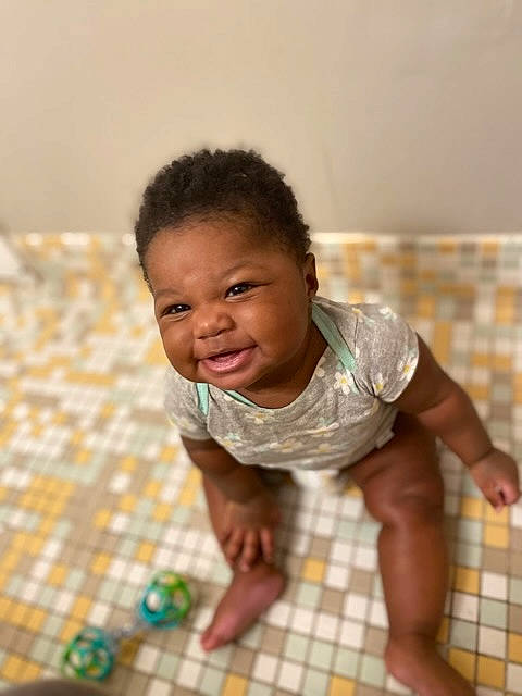 Aniyah joined the competition — help win amazing prizes! baby, baby_toddler_clothing, cheek, child, comfort, crawling, floor, flooring, fun, happy, hardwood, pattern, person, room, shorts, sitting, skin, smile, t_shirt, toddler