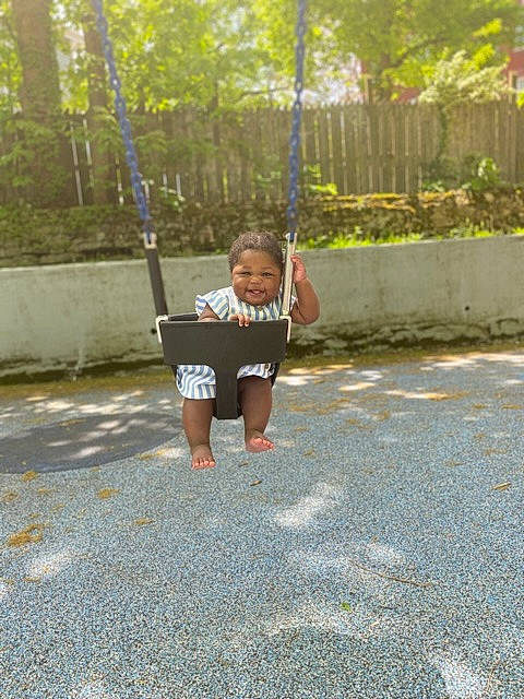 Aniyah joined the competition — help win amazing prizes! asphalt, child, city, electric_blue, fence, fun, grass, happy, leisure, outdoor_play_equipment, person, plant, recreation, road_surface, shorts, sidewalk, sleeve, swing, t_shirt, toddler