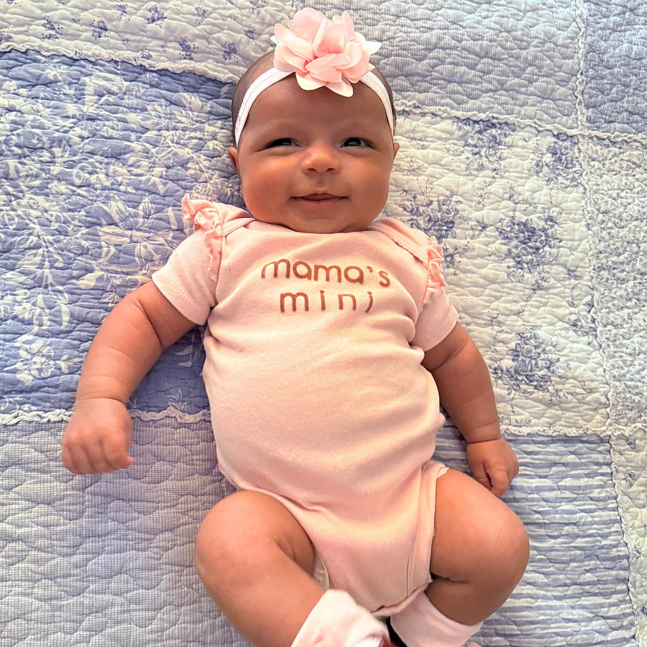 Zorie joined the competition — help win amazing prizes! apparel, baby, cheerful, child, cute, flower, happy, headband, indoors, infant, lying_down, newborn, onesie, patterned, pink, portrait, quilt, smiling, socks, soft_lighting