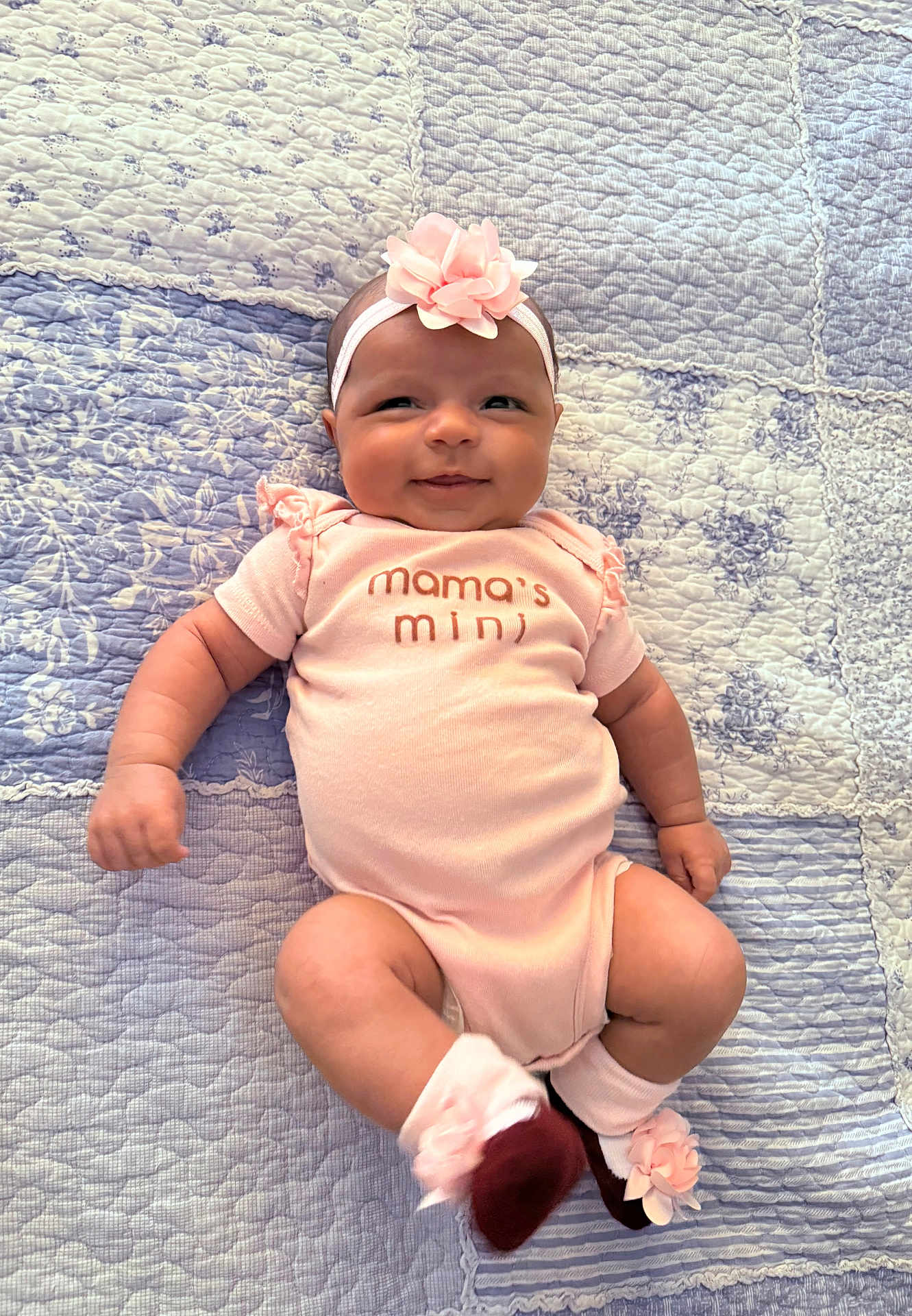 Zorie joined the competition — help win amazing prizes! baby, infant, smiling, pink, headband, flower, onesie, socks, quilt, patterned, lying_down, cute, child, indoors, happy, portrait, soft_lighting, apparel, newborn, cheerful