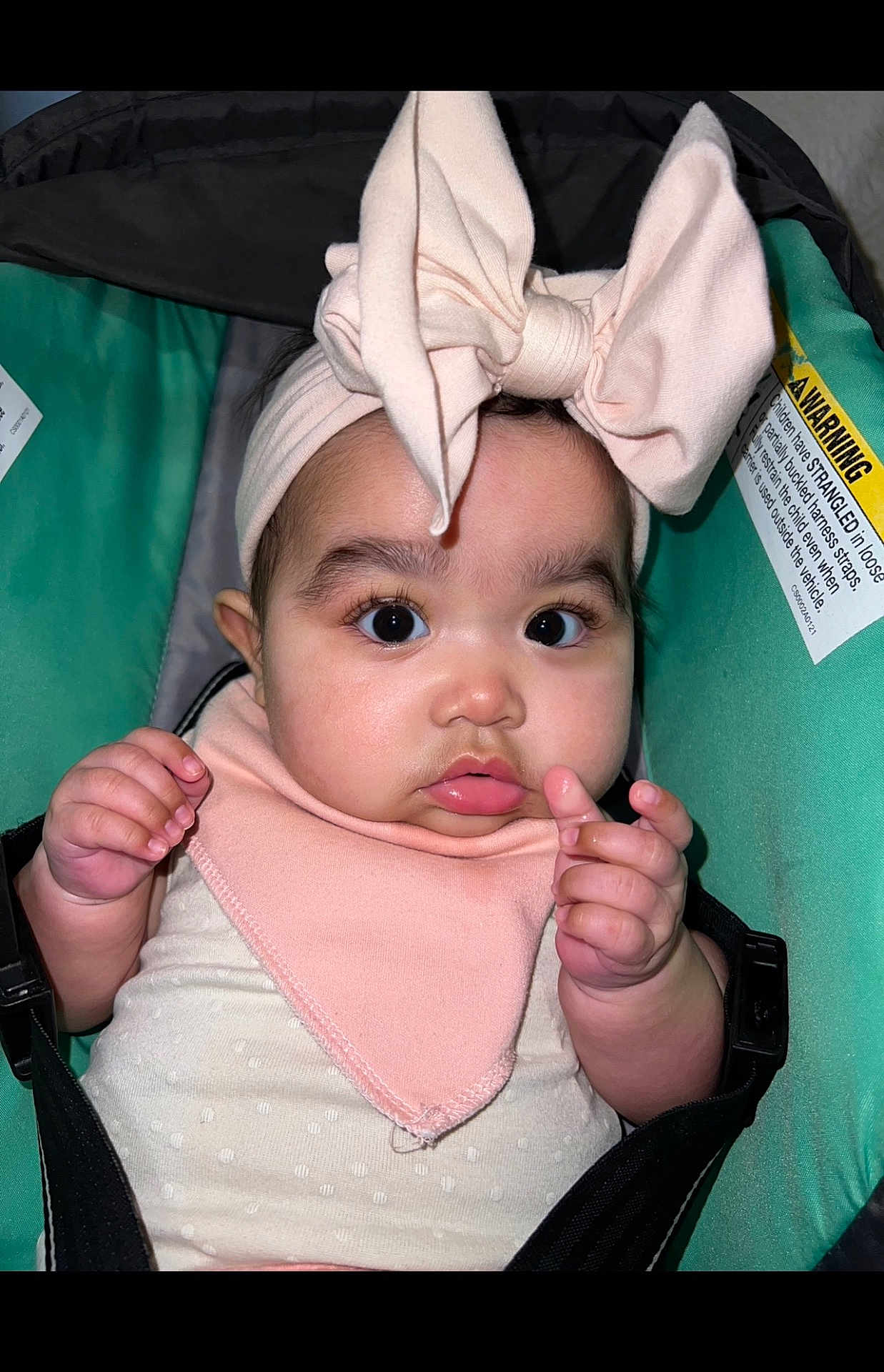 Anahi joined the competition — help win amazing prizes! baby, bib, bow, car_seat, child, close_up, clothing, cute, expression, face, green, hands, headband, indoors, infant, person, pink, portrait, straps, wide_eyes