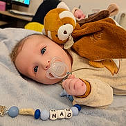 Nao a rejoint le concours — aidez-le/la à gagner de superbes lots ! baby, pacifier, plush_toy, blanket, blue_eyes, infant, cute, soft_toy, clothing, hand, face, indoor, child, lying_down, comfort, home, toy, warm, closeup, peaceful