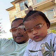 Kiannsha is registered to the contest to win money with this photo: toddler, man, sunglasses, child, outdoor, building, balcony, tree, sky, casual, cute, topknot, shirt, animal_print, giraffe, monkey, leaf, portrait, family, smile