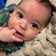 Matthew joined the competition — help win amazing prizes! baby, infant, face, hand, blanket, soft_texture, cute, dinosaur_pattern, clothing, sleepwear, closeup, skin, eyes, fingers, lying_down, cozy, portrait, child, expression, comfort