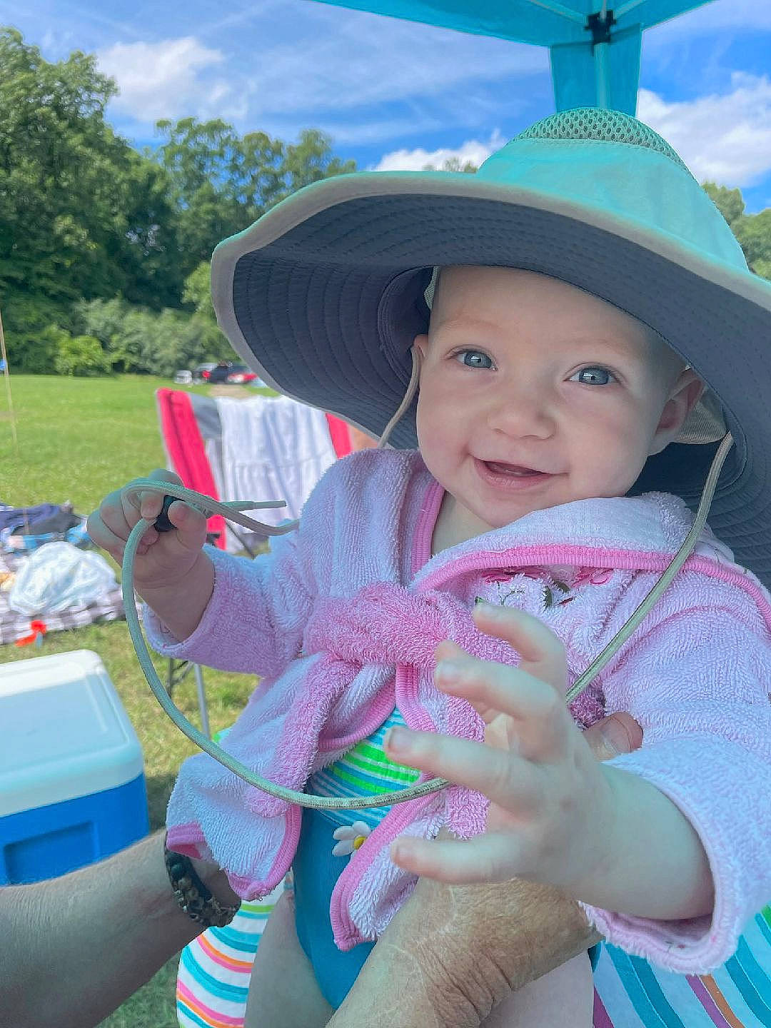 Daisy is registered to the contest to win money with this photo: blue, cap, child, cloud, finger, fun, grass, happy, hat, headgear, headwear, joy, leisure, person, pink, recreation, skin, sky, smile, sun_hat
