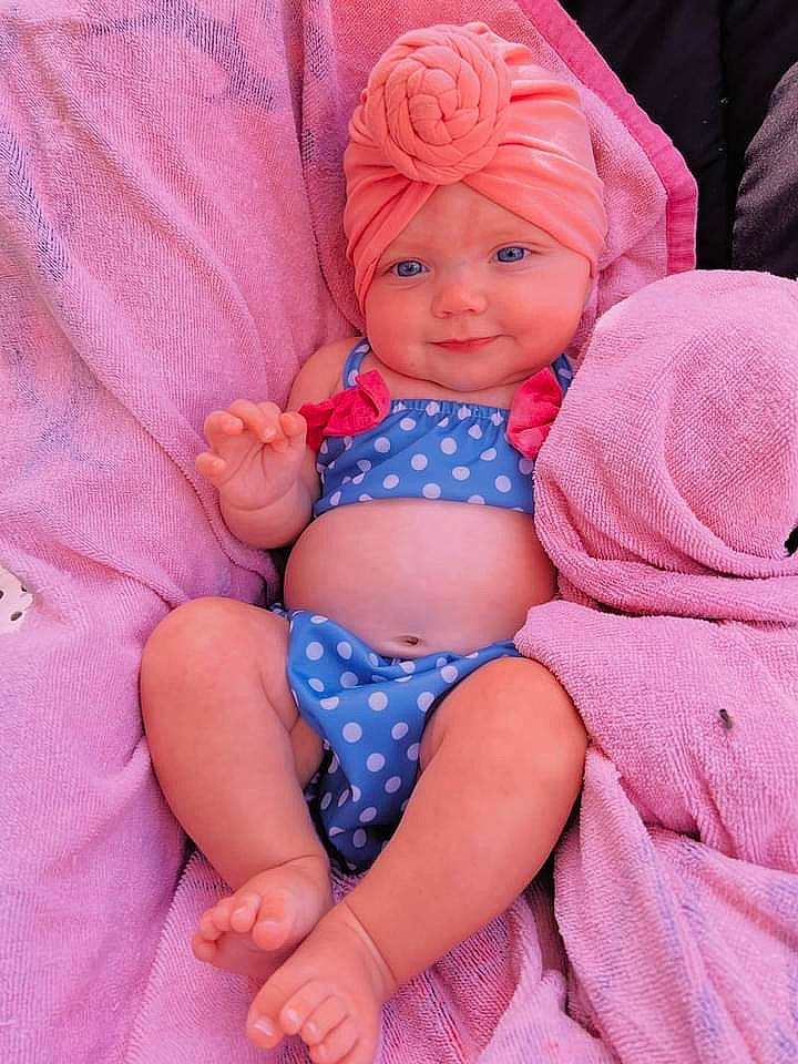 Lakelynn is registered to the contest to win money with this photo: baby_toddler_clothing, cheek, comfort, eye, facial_expression, finger, hairstyle, hand, head, headwear, human_body, joy, lap, leg, lip, mouth, person, pink, purple, skin
