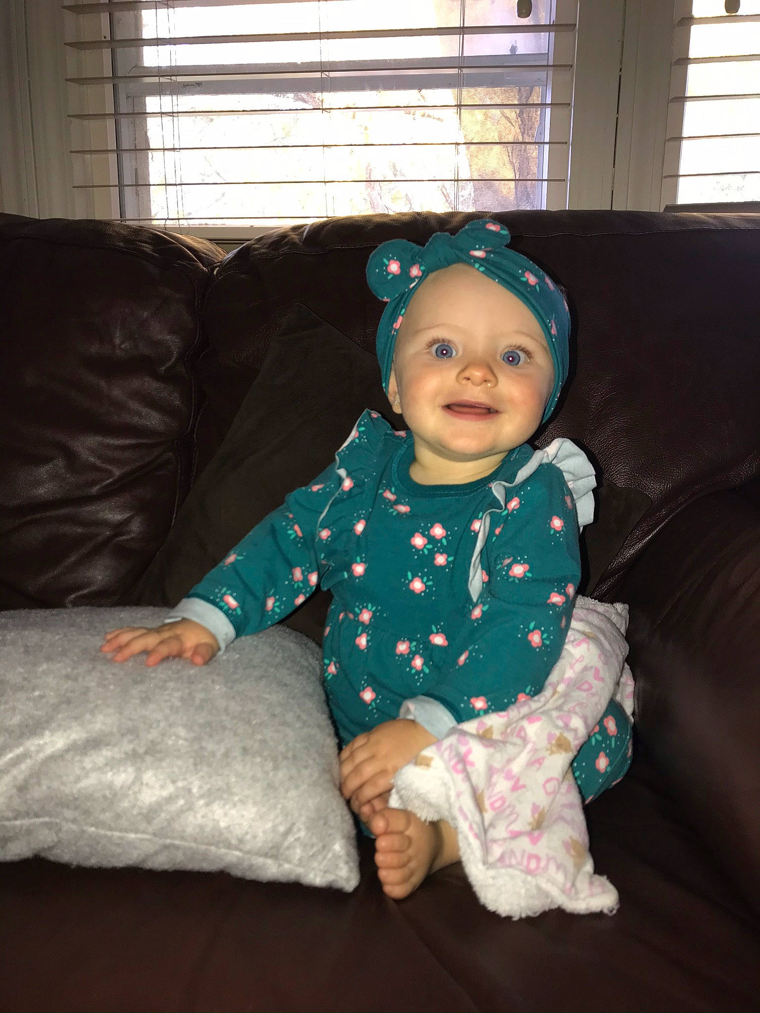 Harlee joined the competition — help win amazing prizes! baby, baby_toddler_clothing, cheek, child, comfort, couch, eye, face, flooring, happy, head, headwear, joy, living_room, pattern, person, room, sitting, sleeve, smile