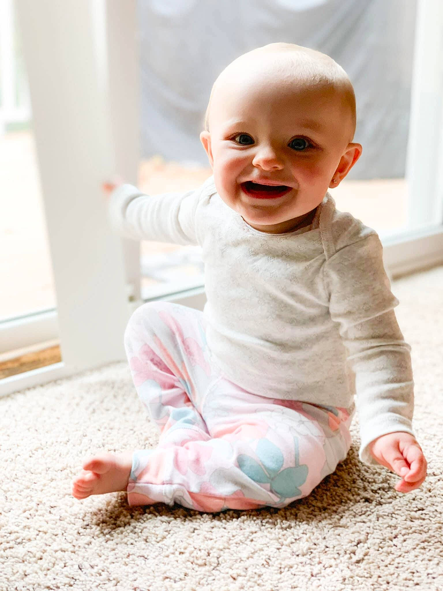 Harlee is registered to the contest to win money with this photo: arm, baby, baby_toddler_clothing, cheek, comfort, face, finger, floor, flooring, happy, iris, joint, joy, lip, person, pink, sitting, skin, sleeve, smile