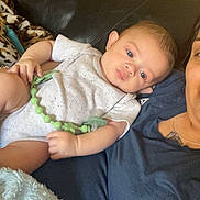 Zarian is registered to the contest to win money with this photo: baby, infant, child, person, adult, couch, leather_couch, blanket, clothing, pacifier, relaxing, indoor, portrait, holding, blue_shirt, white_onesie, skin, face, looking, seated
