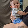 baby, child, smiling, person, tattoo, spiderweb, knee, hand, clothing, shorts, tshirt, indoor, curtain, window, night, adult, holding, skin, portrait, happy