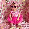 baby, child, pink, sunglasses, bow, dress, tutu, shoes, socks, smiling, portrait, indoor, fashion, cute, toy_brand, barbie, background, patterned, seated, headband