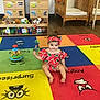 baby, child, colorful, crib, cubby, cute, daycare, floor, headband, indoor, infant, person, photo, play_mat, playroom, rattle, smiling, toy, watermelon_outfit, wooden_furniture