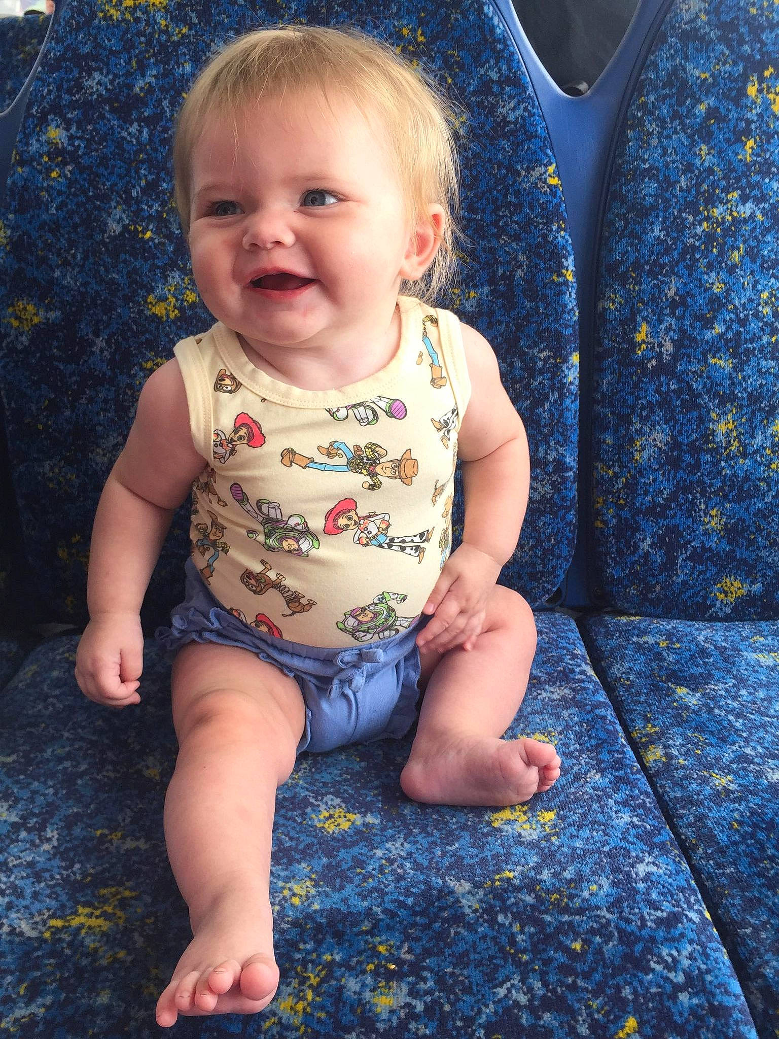 Raya is registered to the contest to win money with this photo: baby, baby_toddler_clothing, blue, cheek, child, eye, face, facial_expression, fun, grass, hairstyle, happy, iris, joy, pattern, person, sitting, skin, sleeve, smile