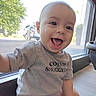 Jensen is registered to the contest to win money with this photo: baby, child, clothing, daylight, face, gray_shirt, happy, head, indoor, infant, laughing, onesie, outdoor, portrait, sitting, smiling, street, sunlight, tree, window