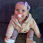 Harley Rose is registered to the contest to win money with this photo: baby, cardigan, child, clothing, couch, cute, footwear, happy, headband, indoor, infant, knitwear, pacifier, person, portrait, purple, sitting, smiling, sock, young_child