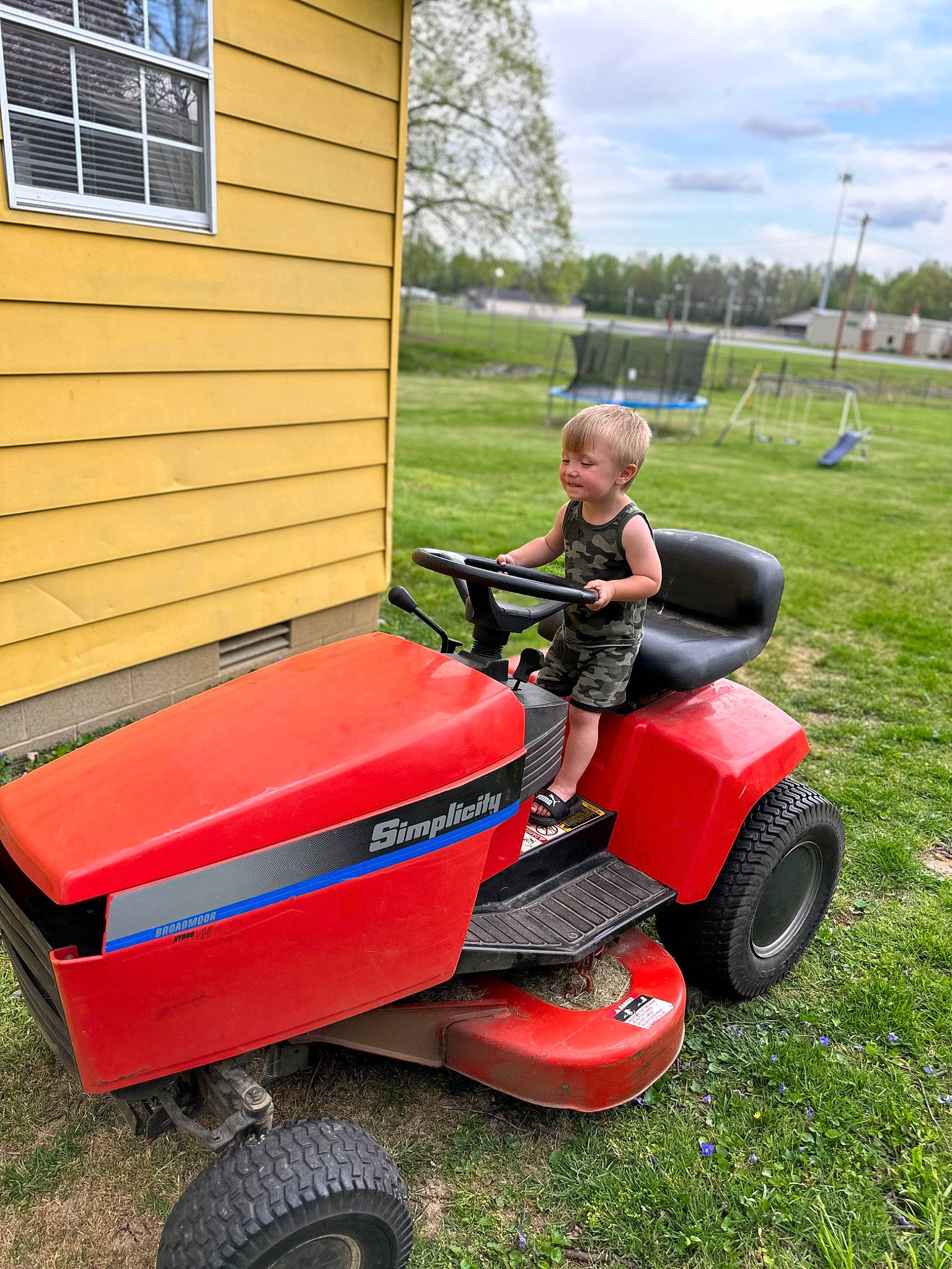 Zaydon is registered to the contest to win money with this photo: automotive_tire, cloud, fender, grass, joy, lawn, lawn_mower, motor_vehicle, mower, outdoor_power_equipment, person, plant, riding_mower, riding_toy, rolling, sky, tire, tread, tree, vehicle