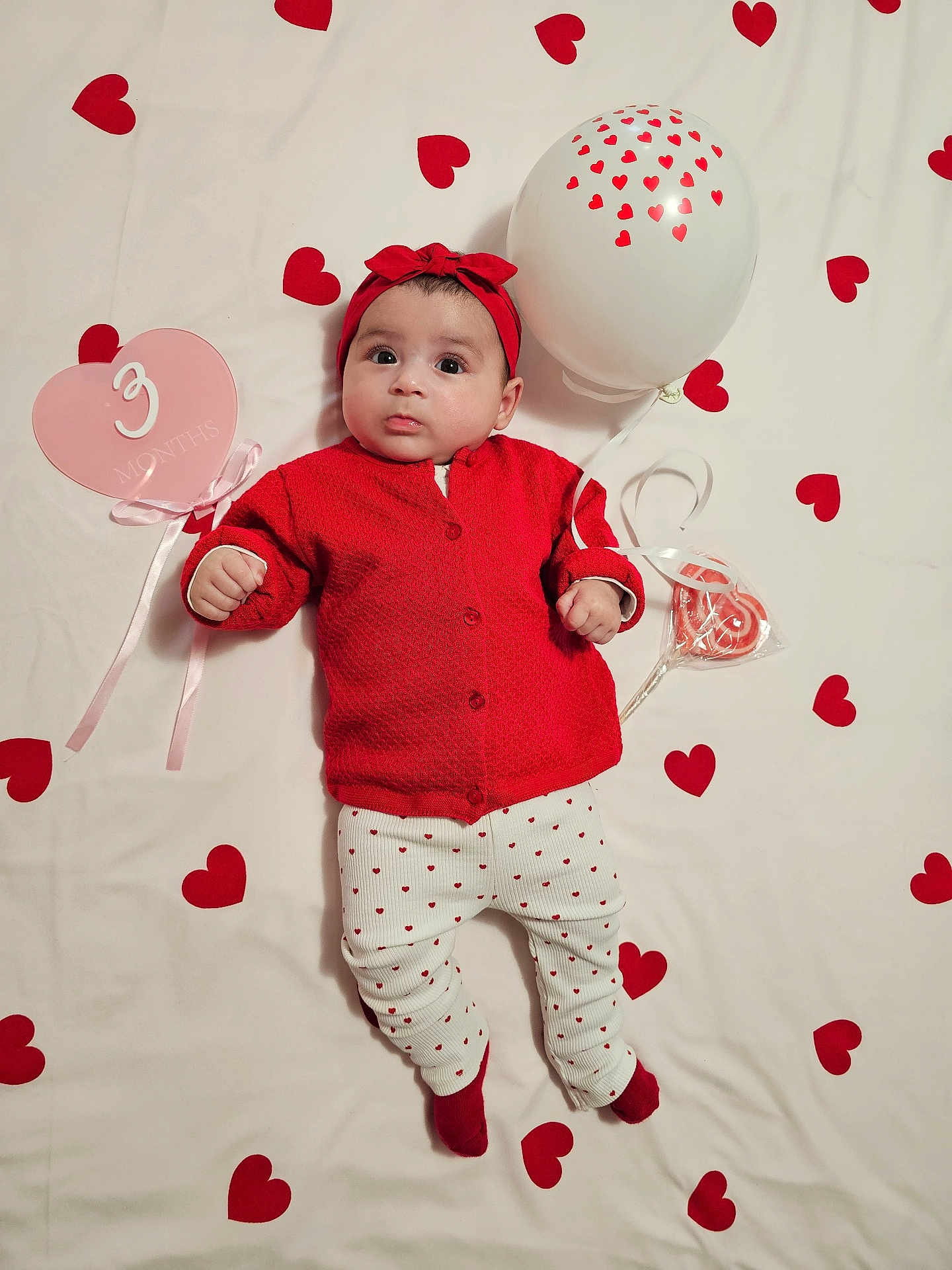 Layanah participe au concours pour gagner de l'argent avec cette photo : baby, infant, three_months, red_clothing, headband, balloon, red_hearts, blanket, lollipop, milestone_card, lying_down, portrait, celebration, cute, wide_eyes, socks, sweater, patterned_leggings, props, valentine_theme