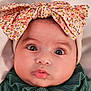 baby, infant, bow, headband, big_eyes, close_up, portrait, cute, lips, eyelashes, cheeks, skin, hat, floral_pattern, green_sweater, gaze, indoors, newborn, adorable, fashion