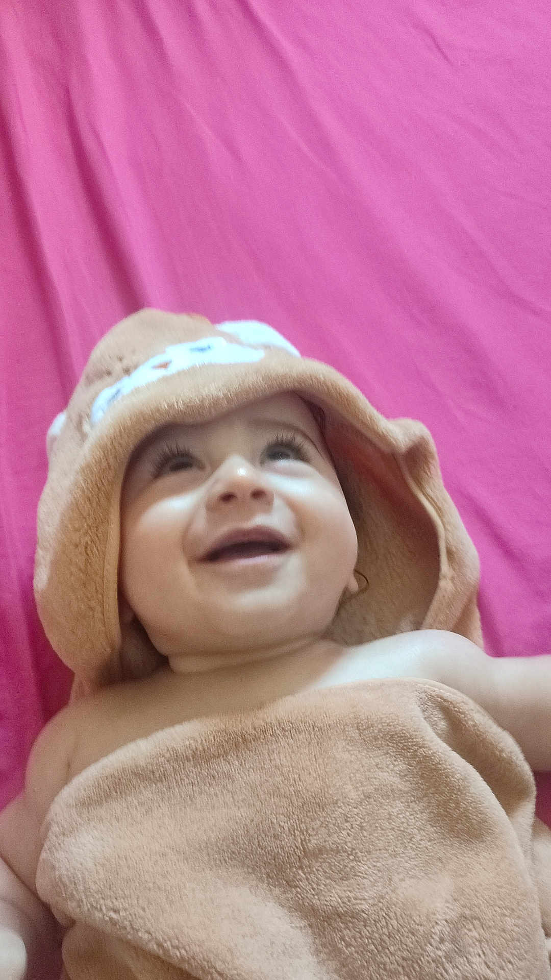 Ramy participe au concours pour gagner de l'argent avec cette photo : baby, smiling, towel, hood, happy, child, infant, face, skin, pink_background, blanket, closeup, portrait, cute, young, expression, lying_down, soft_texture, indoors, warm