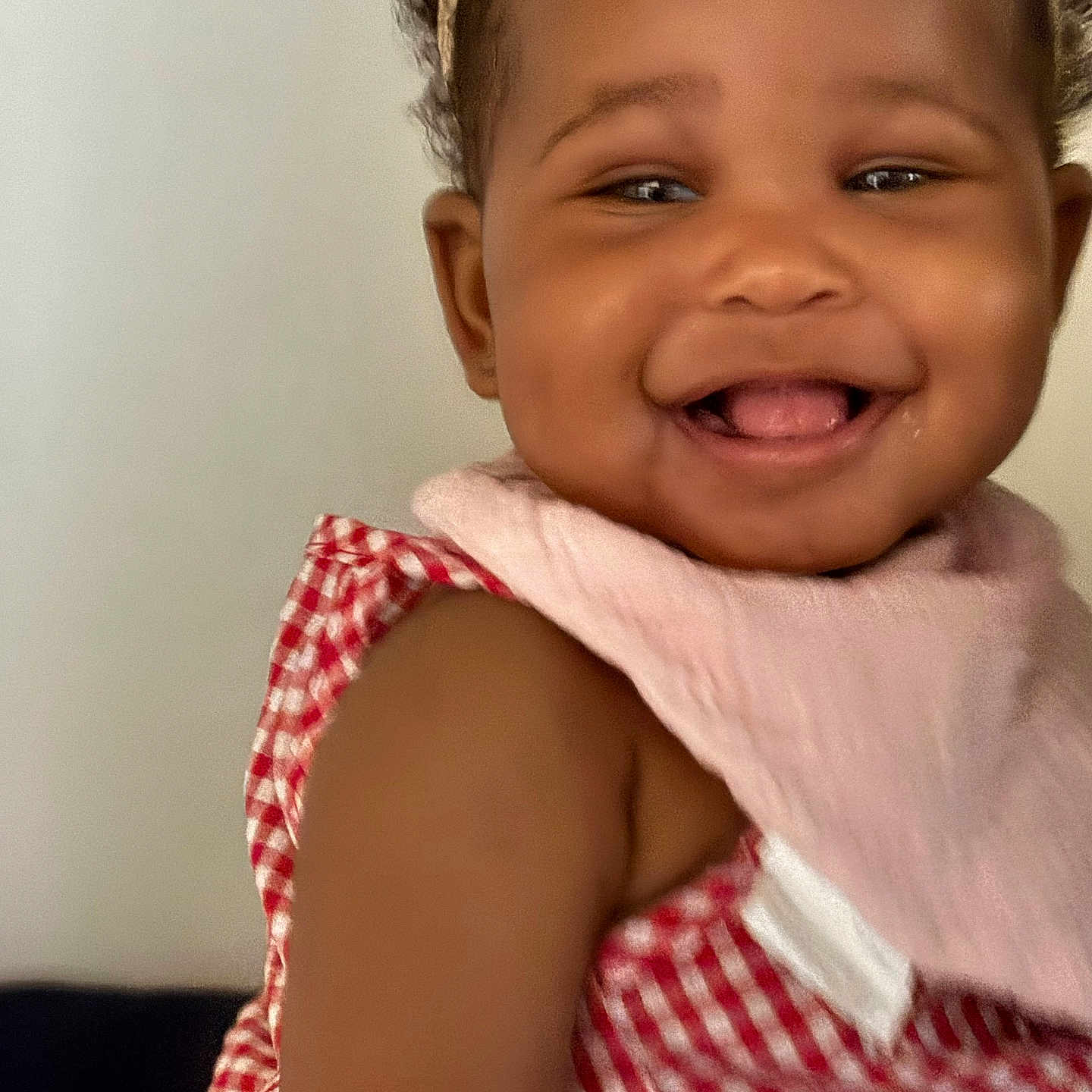 Diary is registered to the contest to win money with this photo: baby, cheeks, child, close_up, clothing, cute, expression, face, happy, headband, indoor, infant, person, pink_bib, portrait, red_checkered_dress, skin, smiling, tongue, young