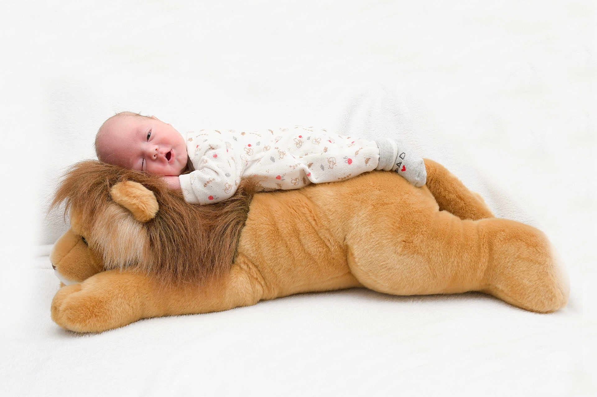 Enzo participe au concours pour gagner de l'argent avec cette photo : baby, infant, stuffed_animal, lion, pajamas, sleeping, soft, plush, cute, child, toy, cozy, lying_down, white_background, peaceful, resting, indoors, young_child, adorable, comfort