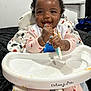 Harmony is registered to the contest to win money with this photo: baby, blanket, child, cozy, curly_hair, cute, feeding, food, happy, high_chair, indoor, infant, messy_face, pajamas, person, playful, smile, spoon, strawberry_pattern, tableware