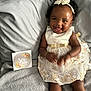 Harmony is registered to the contest to win money with this photo: adorable, baby, bed, blanket, celebration, child, couch, cute, dress, happy, headband, indoors, infant, milestone_card, person, portrait, sitting, six_months, smiling, soft_texture