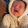 baby, infant, newborn, smiling, closed_eyes, hood, fuzzy_jacket, zipper, cozy, cute, chubby_cheeks, portrait, closeup, indoor, blanket, brown_sleeve, soft_texture, sleeping, happy, person