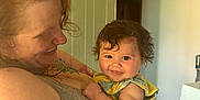 Kleo is registered to the contest to win money with this photo: affection, arm, baby, carpet, child, clothing, doorway, face, furniture, hair, happy, holding, indoor, person, red_hair, room, skin, smiling, tattoo, woman