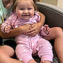 baby, child, smiling, pink_clothing, heart_pattern, sitting, chair, happy, hands, legs, feet, hair_bows, indoor, person, holding, cute, family, toddler, face, closeup