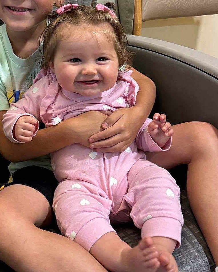 Kleo joined the competition — help win amazing prizes! baby, child, smiling, pink_clothing, heart_pattern, sitting, chair, happy, hands, legs, feet, hair_bows, indoor, person, holding, cute, family, toddler, face, closeup