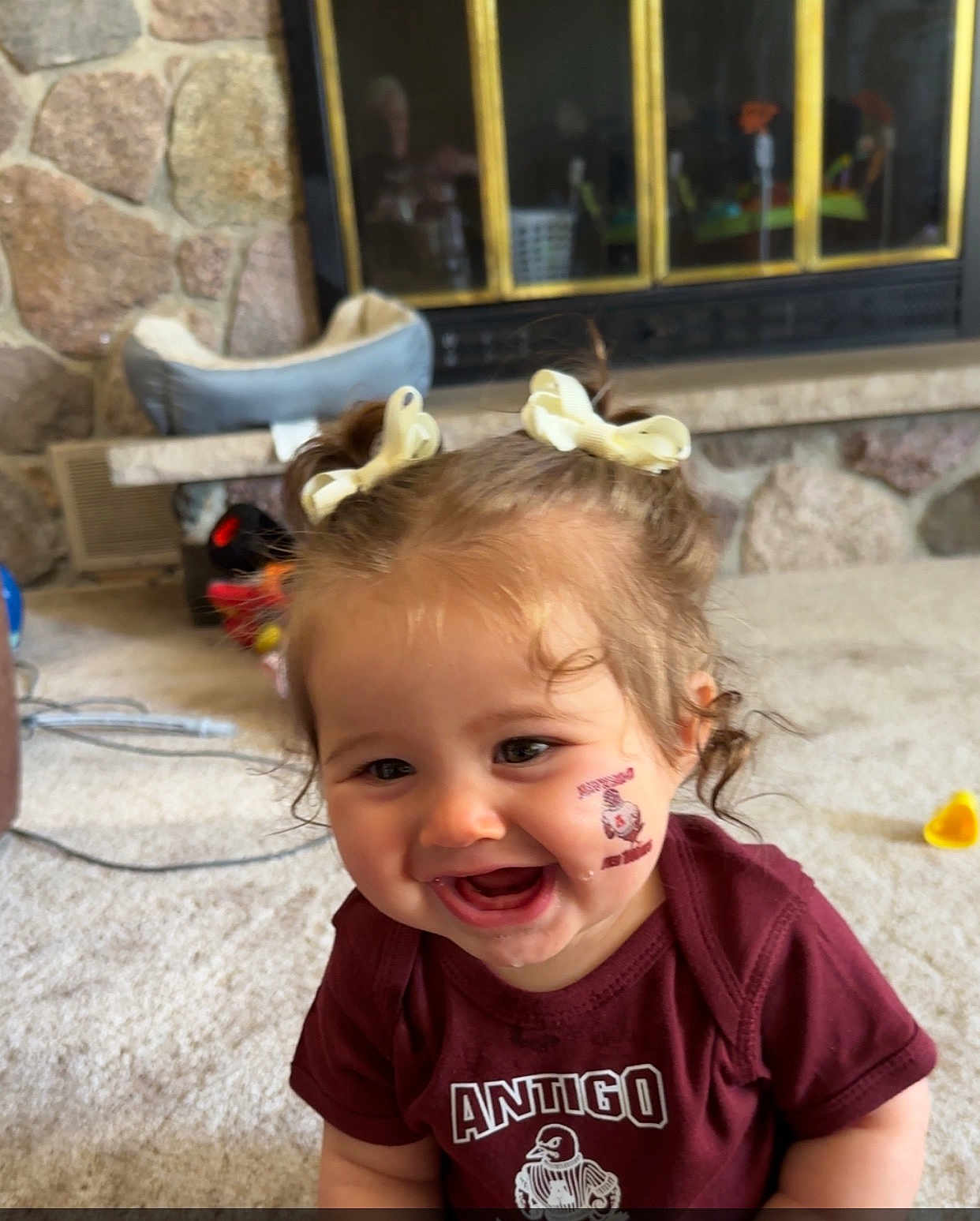 Kleo joined the competition — help win amazing prizes! bows, carpet, child, curly_hair, cute, drool, face, fireplace, happy, indoor, living_room, person, pigtails, shirt, smiling, stone_wall, temporary_tattoo, toddler, toys, young_child