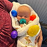 Jett is registered to the contest to win money with this photo: baby, sleeping, blanket, pacifier, colorful_eggs, hand, person, clothing, indoor, comfort, cozy, infant, swaddled, maroon_shirt, furniture, relaxation, cute, peaceful, soft, portrait