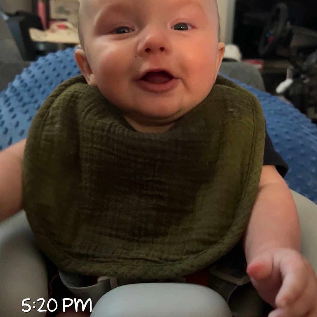 Jett is registered to the contest to win money with this photo: baby, infant, smiling, high_chair, bib, indoor, person, child, furniture, home, blanket, shelf, decor, face, hand, legs, photography, happy, cute, expression