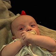 Colby is registered to the contest to win money with this photo: baby, infant, pacifier, blanket, clothing, face, hand, skin, person, lying_down, indoors, cute, young, expression, portrait, child, toddler, sleepwear, comfort, resting